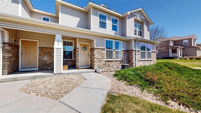 9758 Laredo St Unit 22D, Commerce City, CO 80022 - view of front facade with central AC unit, stone siding, and a porch