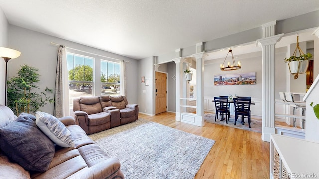 9758 Laredo St Unit 22D, Commerce City, CO 80022 - living area featuring an inviting chandelier, baseboards, ornate columns, and light wood-type flooring