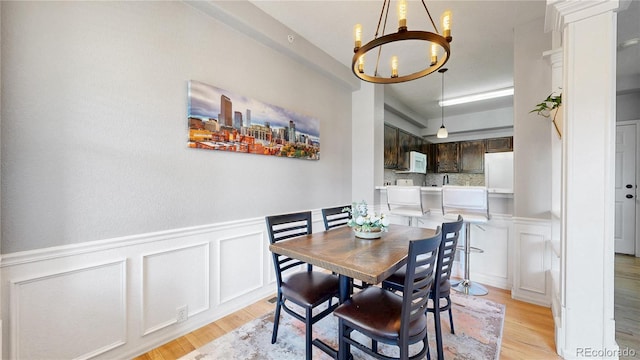 9758 Laredo St Unit 22D, Commerce City, CO 80022 - dining area with a decorative wall, wainscoting, a notable chandelier, and light wood-type flooring