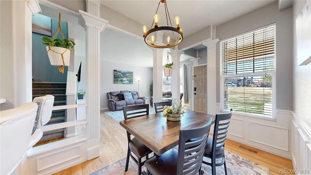 9758 Laredo St Unit 22D, Commerce City, CO 80022 - dining space with light wood finished floors, an inviting chandelier, ornate columns, visible vents, and wainscoting