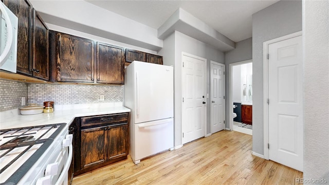 9758 Laredo St Unit 22D, Commerce City, CO 80022 - kitchen with light wood-style flooring, dark brown cabinetry, white appliances, light countertops, and decorative backsplash