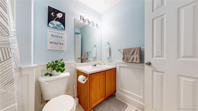 9758 Laredo St Unit 22D, Commerce City, CO 80022 - bathroom featuring wainscoting, vanity, toilet, and tile patterned floors