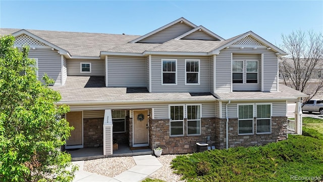 9758 Laredo St Unit 22D, Commerce City, CO 80022 - craftsman-style home featuring a shingled roof, a porch, central AC unit, and stone siding