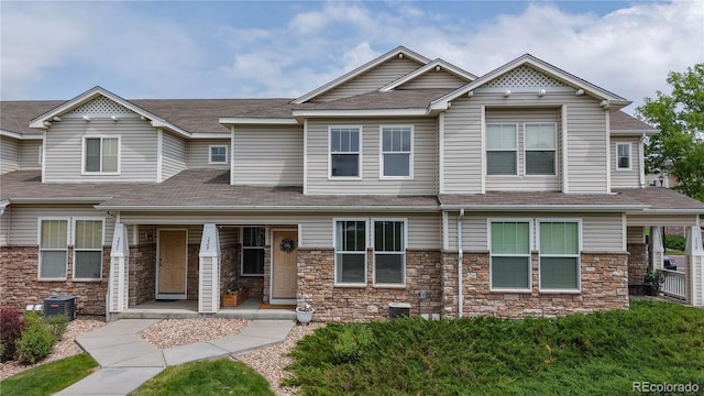 9758 Laredo St Unit 22D, Commerce City, CO 80022 - view of front of house featuring covered porch, stone siding, and a shingled roof