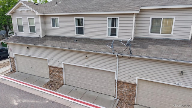9758 Laredo St Unit 22D, Commerce City, CO 80022 - back of property with roof with shingles, stone siding, and an attached garage
