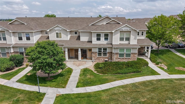 9758 Laredo St Unit 22D, Commerce City, CO 80022 - view of property with covered porch, a front lawn, roof with shingles, and stone siding