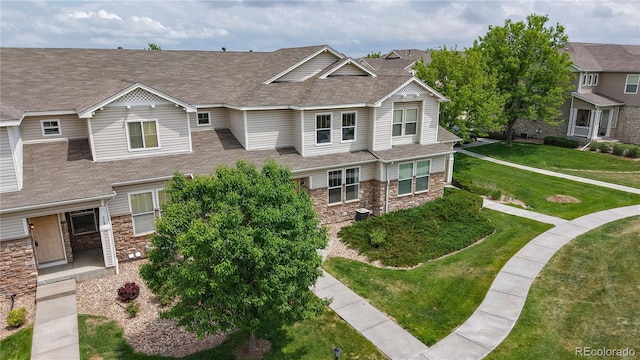 9758 Laredo St Unit 22D, Commerce City, CO 80022 - view of front of home with stone siding, a front yard, and a shingled roof