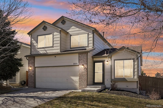 traditional-style home with driveway, brick siding, an attached garage, and fence