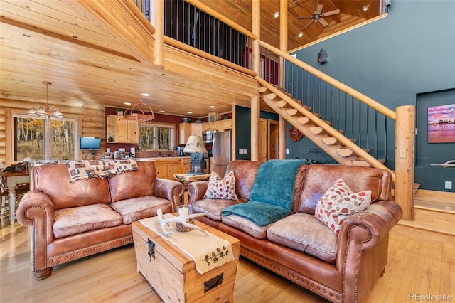 living room with a high ceiling, log walls, wood ceiling, and light hardwood / wood-style floors