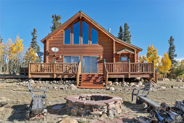 back of house with a wooden deck and an outdoor fire pit