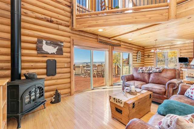 living room featuring a high ceiling, a wood stove, wood ceiling, and light hardwood / wood-style flooring