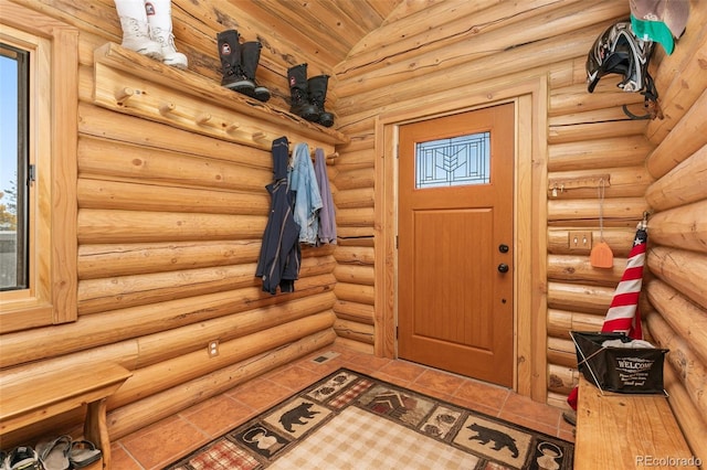 mudroom featuring tile patterned floors, log walls, and vaulted ceiling