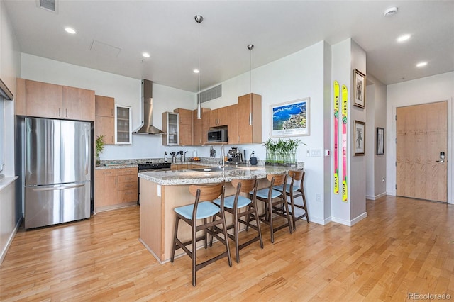 2958 Syracuse St Unit 403, Denver, CO 80238 - kitchen featuring appliances with stainless steel finishes, wall chimney range hood, brown cabinetry, a peninsula, and light wood finished floors