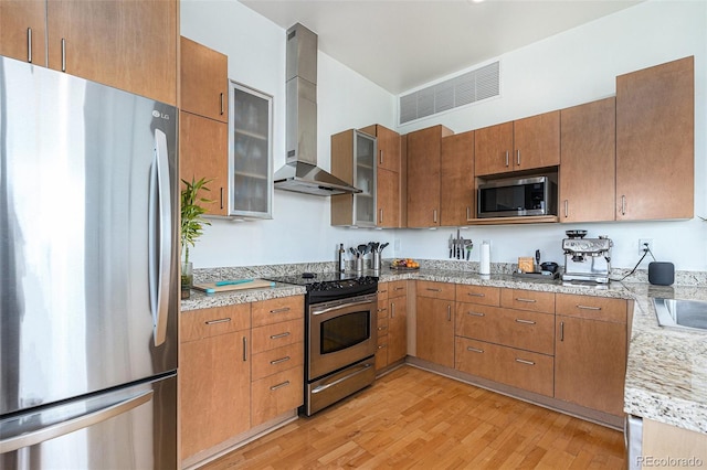2958 Syracuse St Unit 403, Denver, CO 80238 - kitchen featuring appliances with stainless steel finishes, wall chimney range hood, light wood finished floors, and brown cabinets