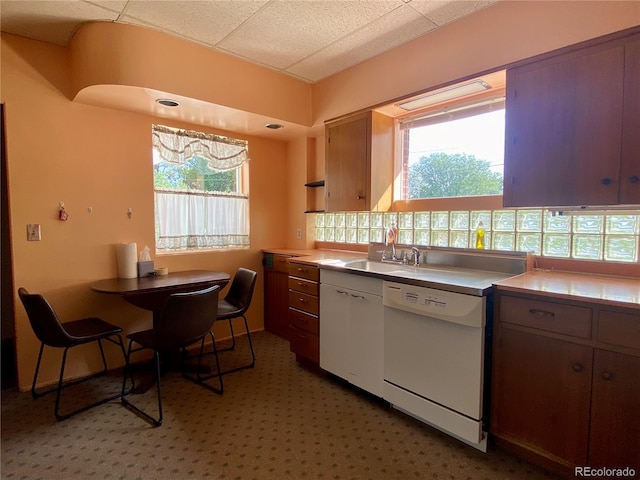 kitchen featuring tile countertops, sink, white dishwasher, and a wealth of natural light