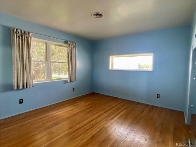 empty room with hardwood / wood-style flooring and plenty of natural light