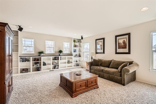 carpeted living area with built in shelves and recessed lighting
