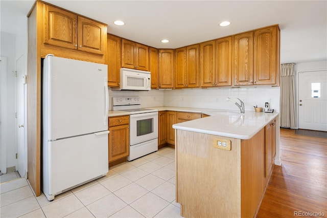 1840 E 84th Ave, Denver, CO 80229 - kitchen featuring white appliances, a peninsula, decorative backsplash, brown cabinetry, and light countertops