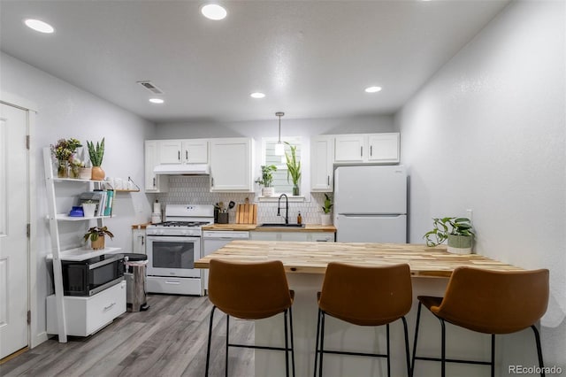 2829 W 53rd Ave Unit 104, Denver, CO 80221 - kitchen featuring white appliances, wooden counters, a kitchen breakfast bar, white cabinetry, and recessed lighting