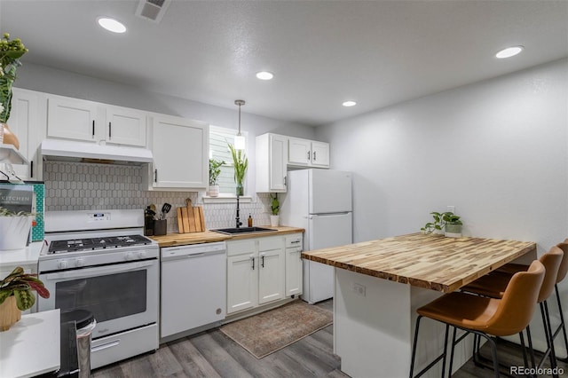 2829 W 53rd Ave Unit 104, Denver, CO 80221 - kitchen with white appliances, under cabinet range hood, wood counters, a breakfast bar area, and white cabinets