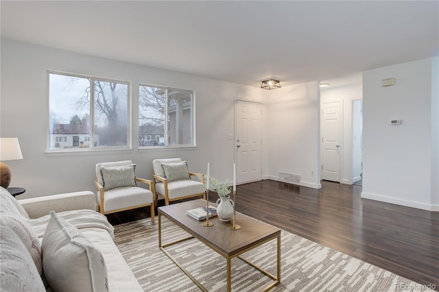 living room featuring visible vents, baseboards, and wood finished floors