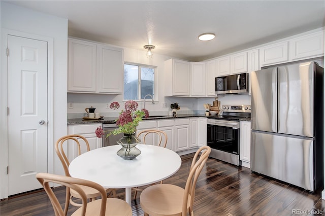 kitchen featuring dark countertops, appliances with stainless steel finishes, white cabinets, and dark wood-style flooring