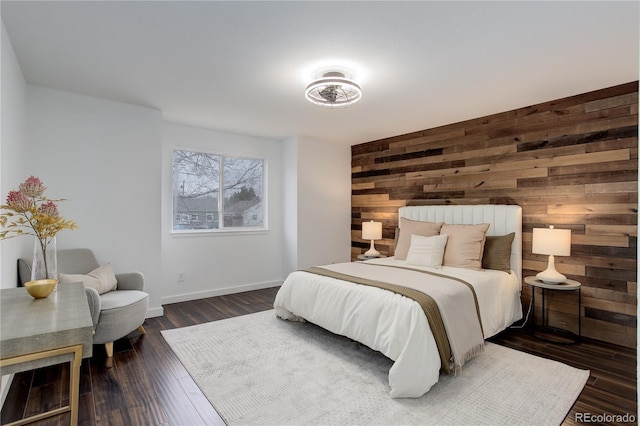 bedroom with baseboards, dark wood-type flooring, an accent wall, and wooden walls