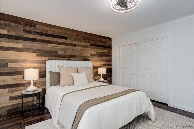 bedroom featuring a closet, wooden walls, and dark wood finished floors