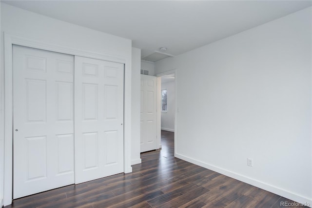 unfurnished bedroom with a closet, baseboards, and dark wood finished floors