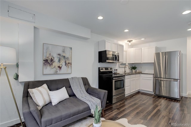 kitchen featuring recessed lighting, dark wood-style flooring, a sink, stainless steel appliances, and white cabinetry