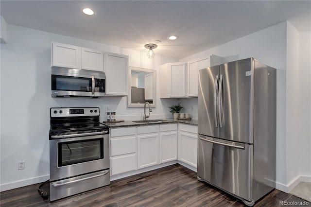 kitchen featuring dark stone countertops, white cabinets, appliances with stainless steel finishes, and a sink