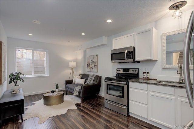 kitchen featuring dark stone countertops, recessed lighting, appliances with stainless steel finishes, white cabinets, and dark wood-style flooring