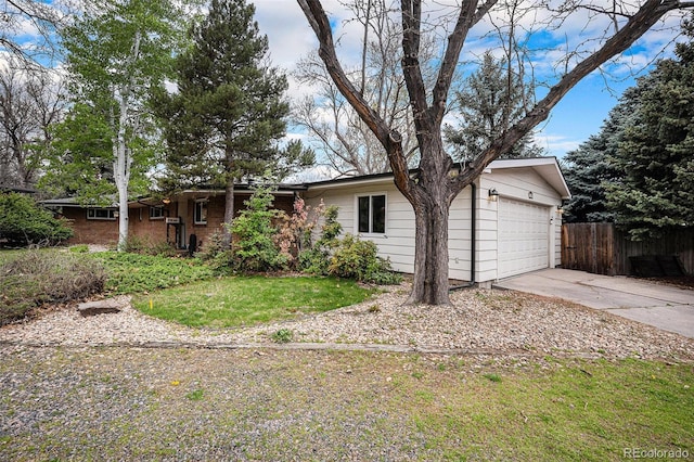 ranch-style house featuring fence, an attached garage, driveway, and a front yard