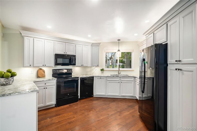 kitchen with dark wood finished floors, a sink, light stone counters, black appliances, and recessed lighting