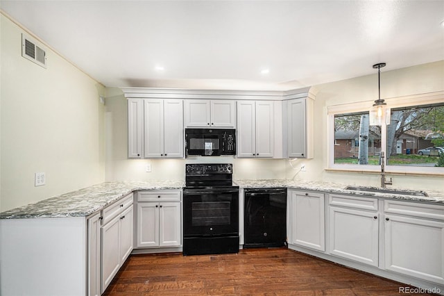 kitchen with visible vents, light stone countertops, dark wood-style floors, a sink, and black appliances