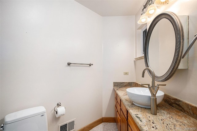 bathroom with baseboards, vanity, toilet, and visible vents