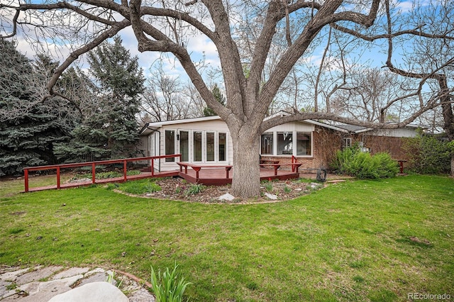 back of property with a yard, brick siding, and a deck