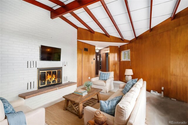 living area with wooden walls, vaulted ceiling with beams, and a fireplace