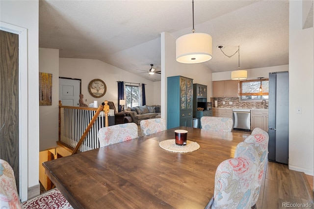 dining space with lofted ceiling, a healthy amount of sunlight, sink, and light hardwood / wood-style floors