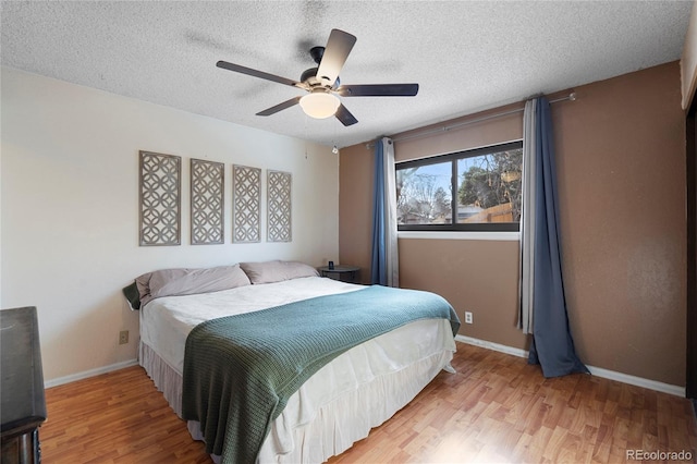 bedroom with ceiling fan, light hardwood / wood-style floors, and a textured ceiling