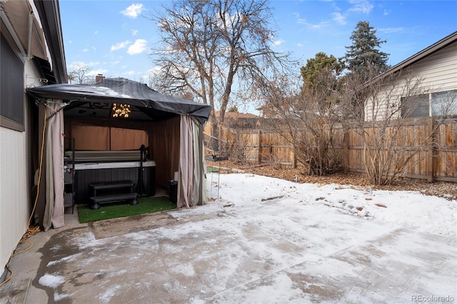 yard covered in snow featuring a gazebo, a hot tub, and a patio area