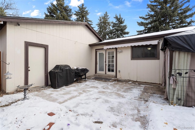 snow covered back of property featuring a patio