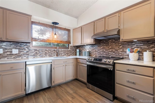 kitchen featuring pendant lighting, sink, appliances with stainless steel finishes, hardwood / wood-style floors, and vaulted ceiling