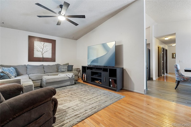 living room with ceiling fan, vaulted ceiling, hardwood / wood-style floors, and a textured ceiling