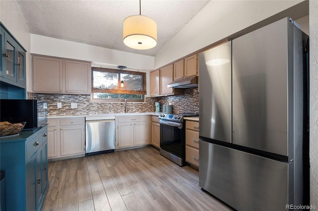 kitchen featuring tasteful backsplash, appliances with stainless steel finishes, pendant lighting, and light wood-type flooring