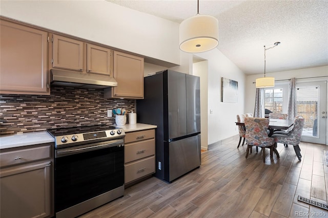 kitchen featuring pendant lighting, lofted ceiling, stainless steel appliances, and decorative backsplash