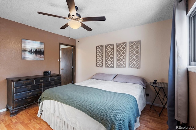 bedroom with ceiling fan, a textured ceiling, and light wood-type flooring