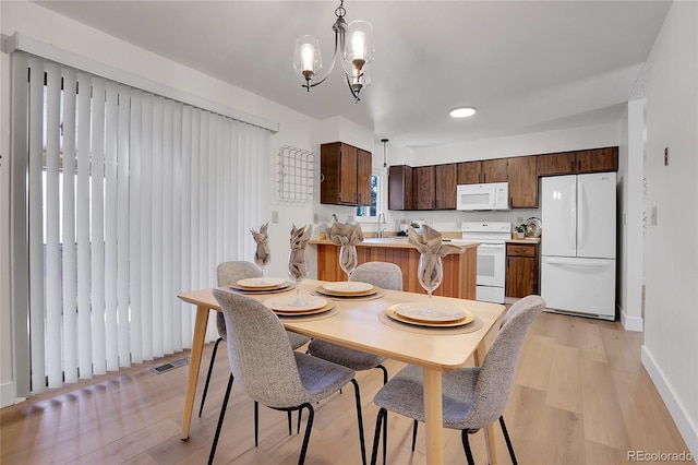 dining area with sink, light hardwood / wood-style floors, and a notable chandelier