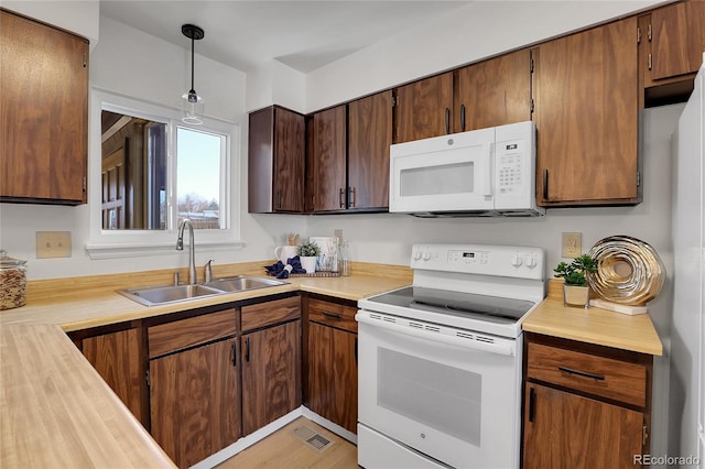 kitchen featuring sink, white appliances, and decorative light fixtures