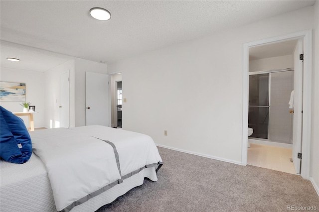 bedroom with ensuite bathroom, a textured ceiling, and carpet